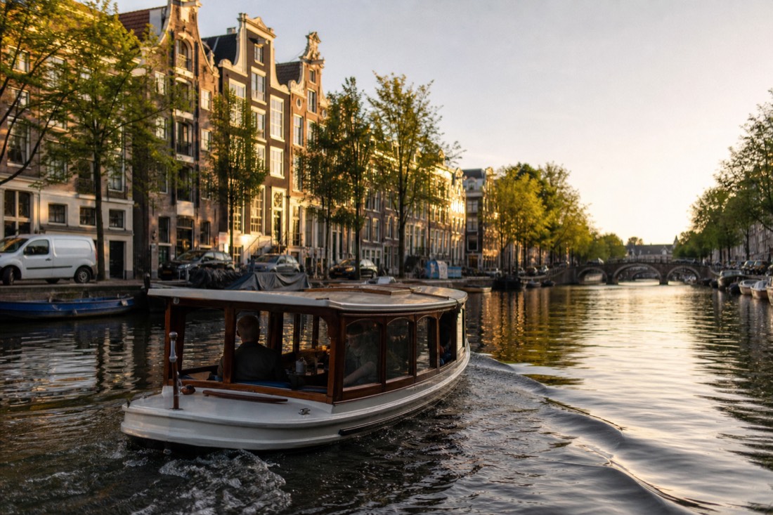 A classic saloon boat gliding along an Amsterdam canal at golden hour, no text, no logos, no people