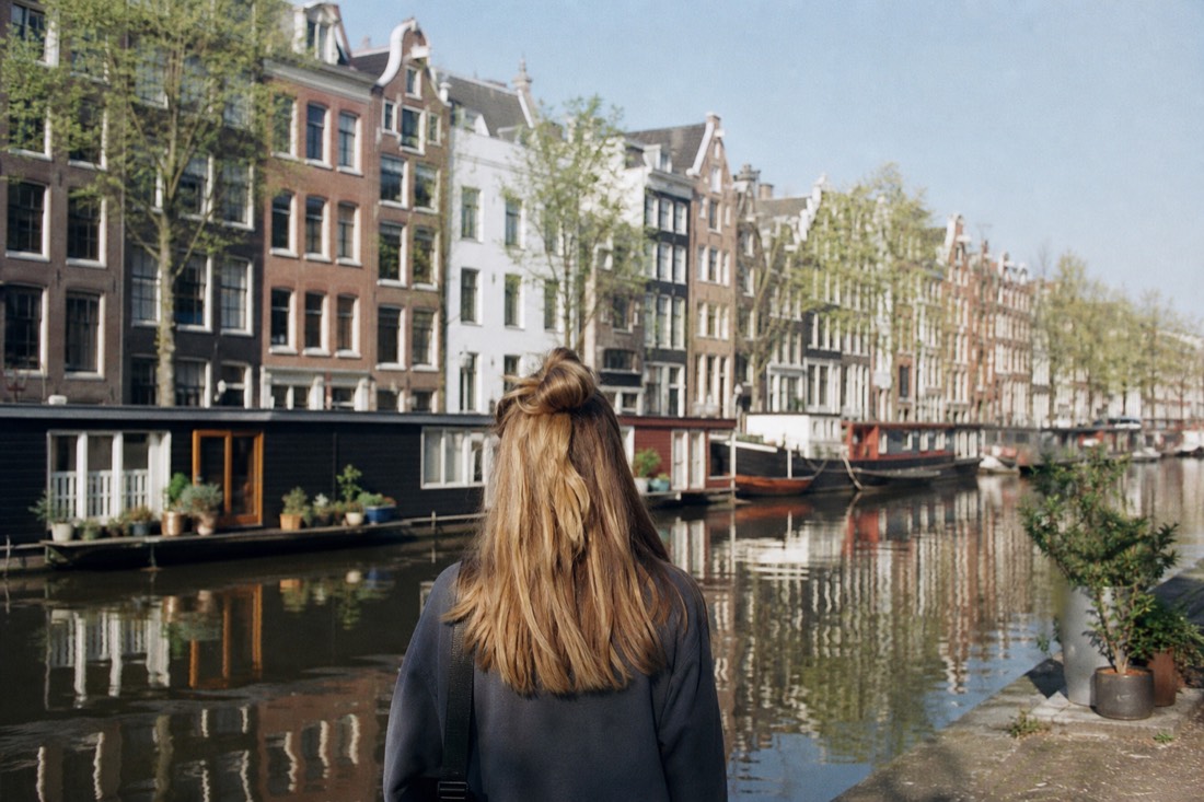 A classic Amsterdam canal lined with narrow gabled houses and moored boats, no text, no logos, no people.