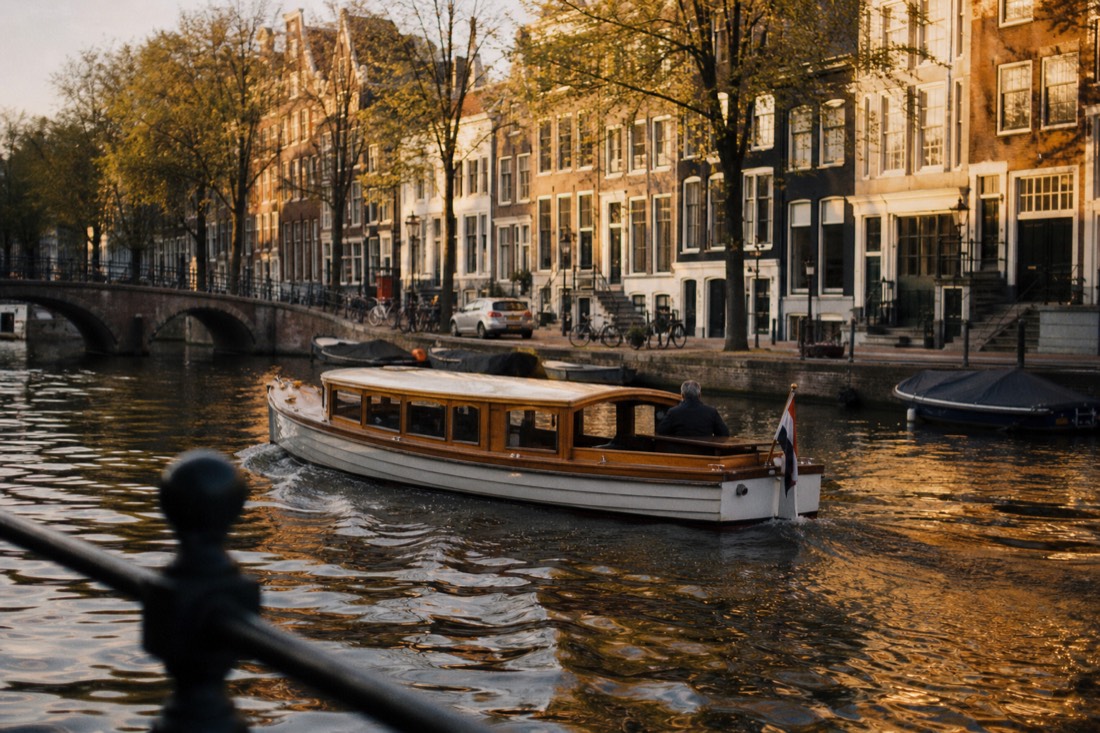 A classic saloon boat gliding along the Herengracht at golden hour, no text, no logos, no people.